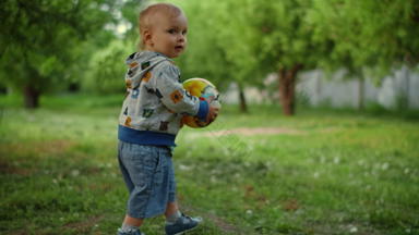男孩携带球森林特写镜头微笑蹒跚学步的男孩运行在户外